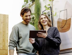 ABB zeigt ein Paar bei der komfortablen Steuerung Ihres Smart Homes per Tablet dank „Busch-free@home“ von Busch-Jaeger.
