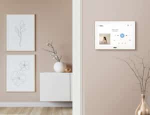 ABB zeigt 'Busch-free@home' von Busch-Jaeger mit einem modernen, eleganten Smart-Home-Bedienpanel SmartTouch 10 Zoll in Weiss auf rosafarbener Wand zur zentralen Steuerung vernetzter Funktionen im Wohnbereich.