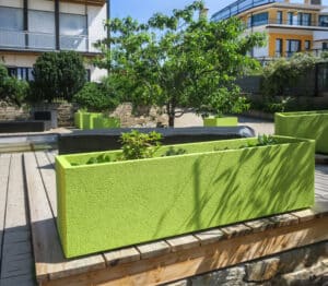 Mehrere hohe, grüne längliche Blumenkästen für den Außenbereich in einer modernen Wohnsiedlung von Blumentrog-Flexi.