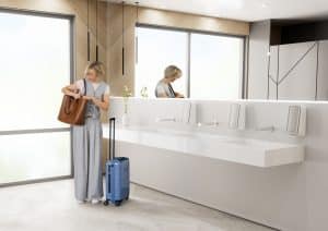 Reisende in einem Waschraum mit Seifenspendern aus der CWS PureLine in Silber.
