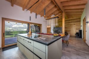 Offene Wohnküche im Dachgeschoß eines Hauses mit Dachschräge, Holzdecke, Holz-Alu-Schiebetüren zum Balkon von ERLER Haus.
