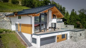 Satteldachvilla im Chalet-Stil mit Fassadenelementen aus Holz, Glas und Stein mit Doppelgarage, Pool und zwei Eingängen von ERLER Haus.