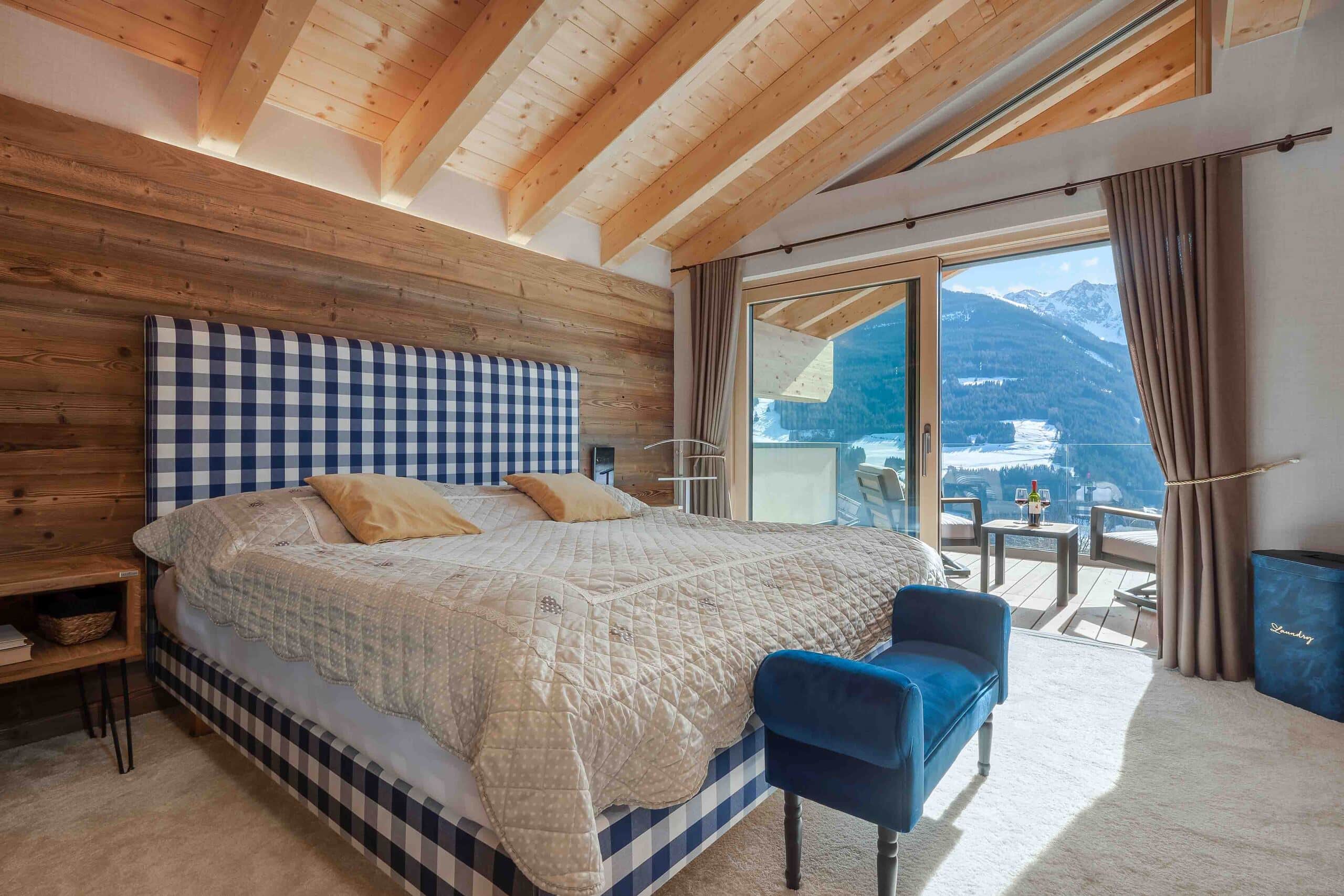 Schlafzimmer mit indirekt beleuchtetem Sichtdachstuhl, Teppichboden und Balkon mit Holz-Alu-Schiebetüren von ERLER Haus.