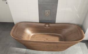 Ein Badezimmer mit mattgrauen uns glänzend-weissen Fliesen und einer freistehenden Massivholzbadewanne namens "Relax Comfort" von FESTWOOD.