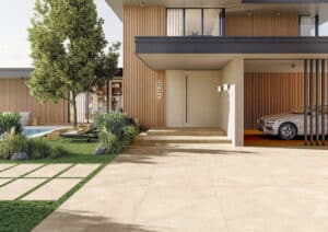Eine moderne Villa mit fließendem Übergang zwischen Eingangs‑ und Terrassenbereich mit beigen großformatigen Steinoptik‑Außenfliesen welche ebenfalls als Trittsteine am Rasen verwendet werden von Fliesendorf.