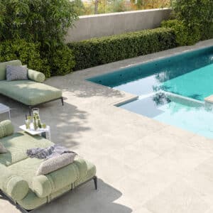 Ein großzügiger Terrassen‑ und Poolbereich mit stilvollen Outdoormöbeln und beigen Steinoptik‑Fliesen die nahtlos für die Poolumrandung eingesetzt wurden von Fliesendorf.