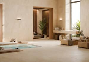 Ein heller Indoor‑Pool‑Spa‑Bereich mit großformatigen beige XXL‑Steinoptik‑Fliesen an Wand und Boden, stilvollen Lounge‑Liegen, sanftem Licht und minimalistischer Wellness‑Atmosphäre von Fliesendorf.