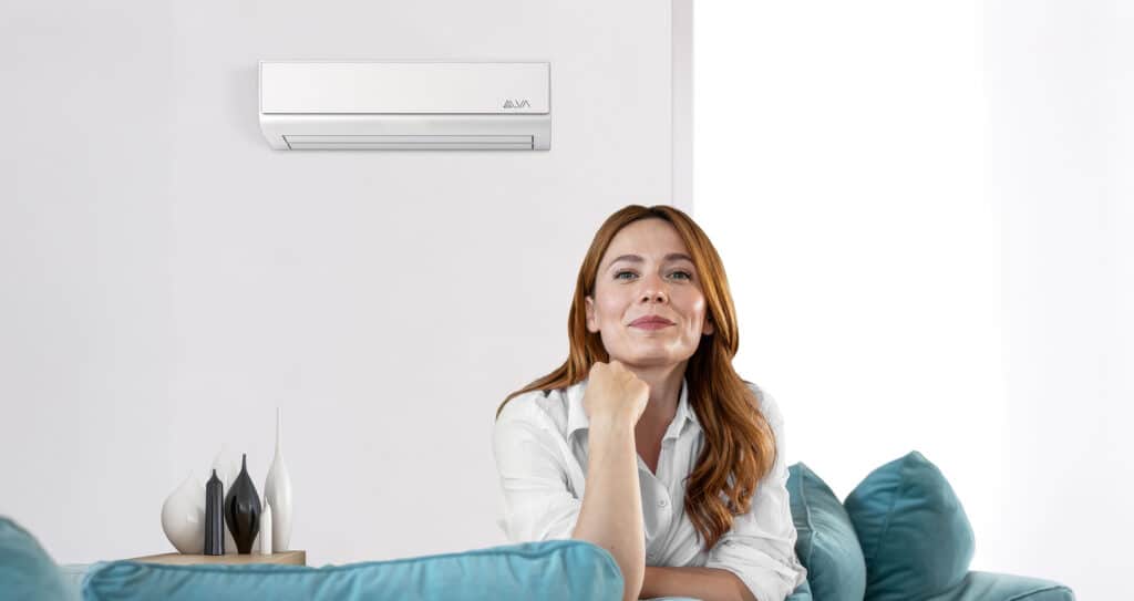 Eine Frau genießt das angenehm temperierte Wohnzimmer mit einer Klimaanlage von ALVA, die kühlen und heizen kann.