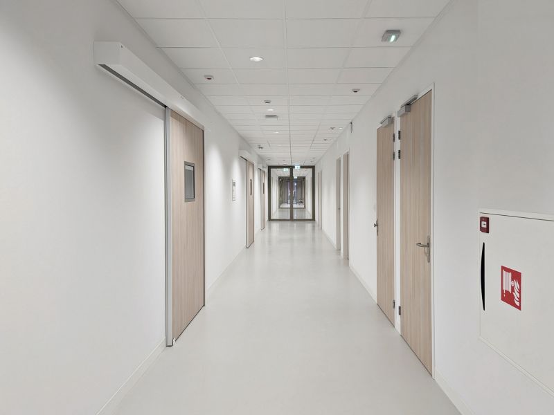 Gerflor zeigt einen Gang in einem öffentlichen Gebäude mit hellgrauem Linoleum Bodenbelag.