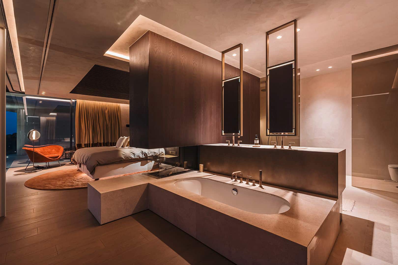 Gessi zeigt das ans Schlafzimmer angeschlossene offene Bad mit Kamin, Wanne und Armaturen aus der Serie Inciso.