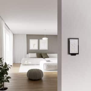 Ein wandmontiertes schwarzes G1‑Bedien‑ und Anzeigegerät der zweiten Generation mit Glasfront und integriertem Temperatur‑ sowie Feuchtigkeitsmess‑Modul zur Smart‑Home‑Steuerung im Innenraum von Gira.