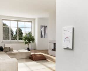 Ein wandmontiertes weißes Gira G1 Bedien‑ und Anzeigegerät der zweiten Generation mit Glasfront zur Steuerung von Smart‑Home‑Funktionen im Wohnraum von Gira.
