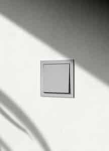 Ein Gira F200 flach Wippschalter in Schattengrau mit schlankem Rahmen an einer hellen Wand.