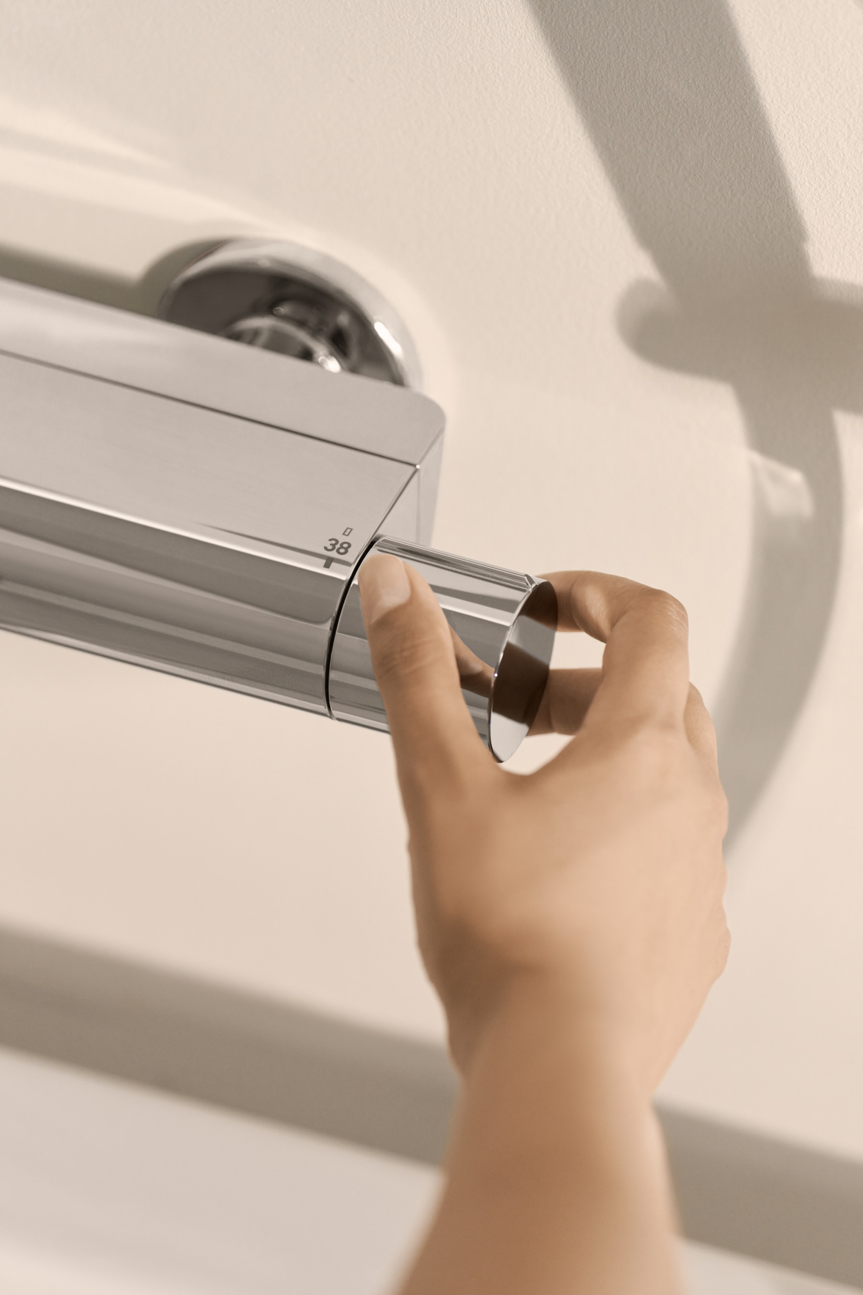 HANSA zeigt den Drehregler mit Thermostat der verchromten glänzenden Wandarmatur Viva.