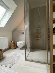 Hansa zeigt eine Regendusche und eine Handdusche, beide mit rundem Kopf und in silber, in einem Badezimmer eines Hotels.