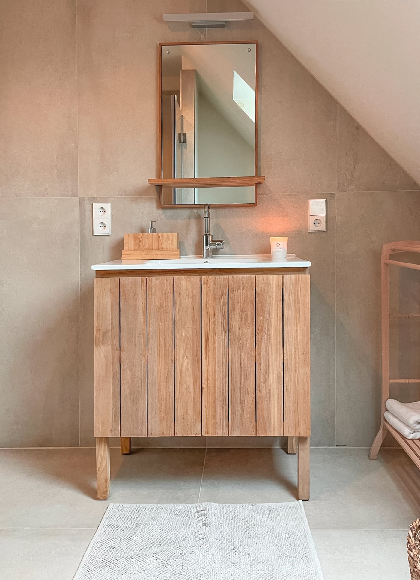 Hansa zeigt einen Waschtisch aus Holz mit Einfachwaschbecken, Armatur mit Schwanenhals in silber in einem Badezimmer eines Hotels.