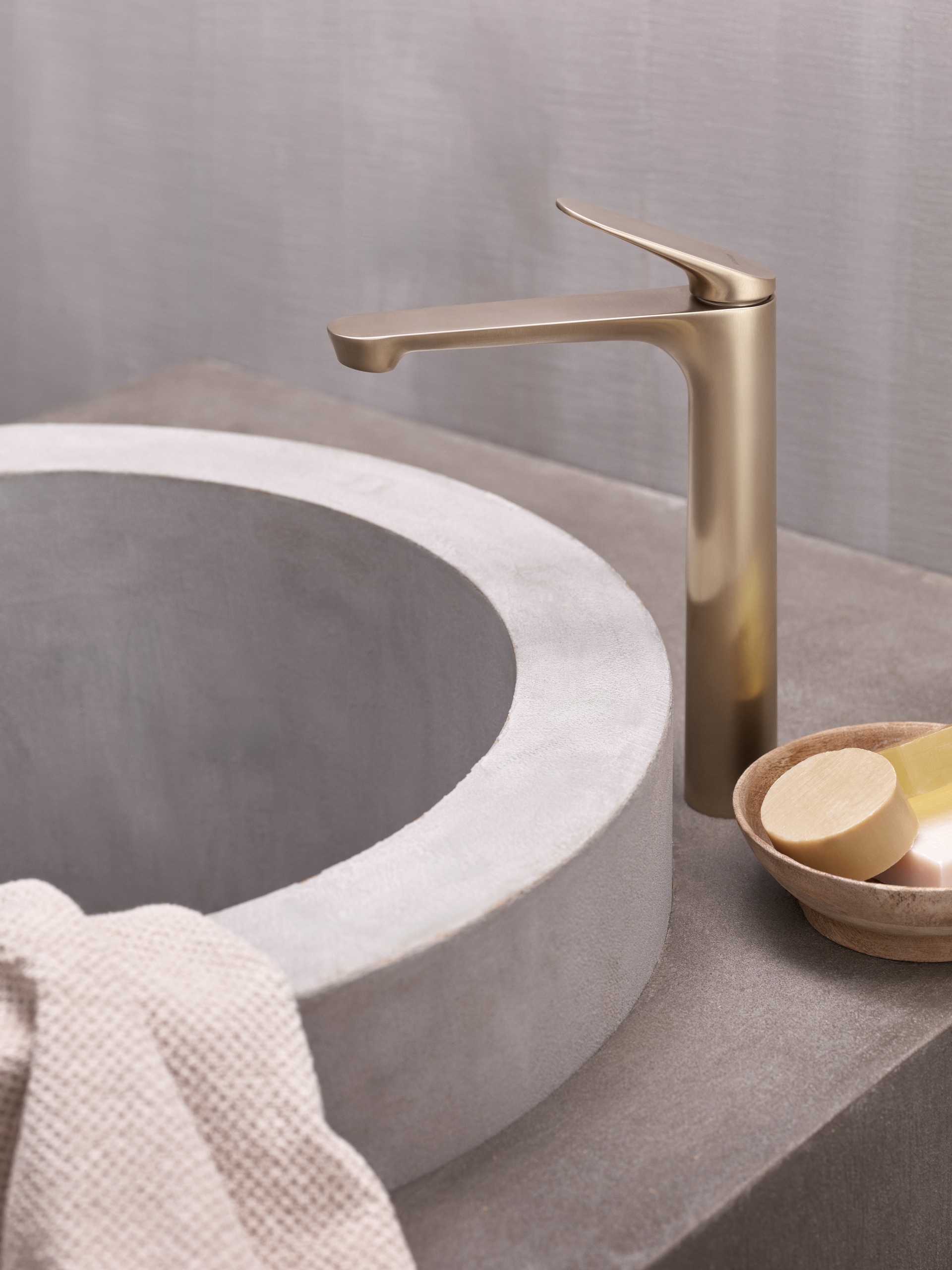 Hansa präsentiert eine elegante Armatur in gold mit obenliegendem Hebel und freistehend neben dem Beckenrand in einer Nahaufnahme.