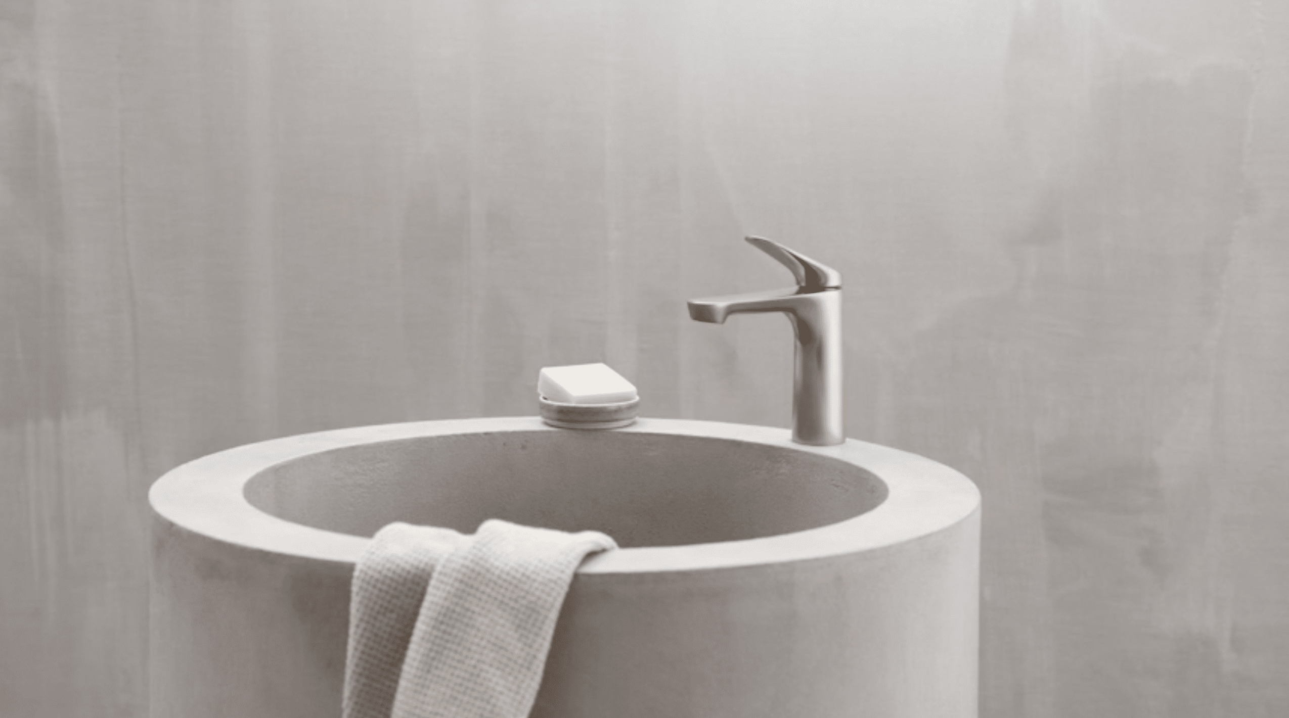 Hansa präsentiert einen Wasserhahn aus der neuen Serie HANSAGENESIS in silber auf einem freistehendem Waschbecken.
