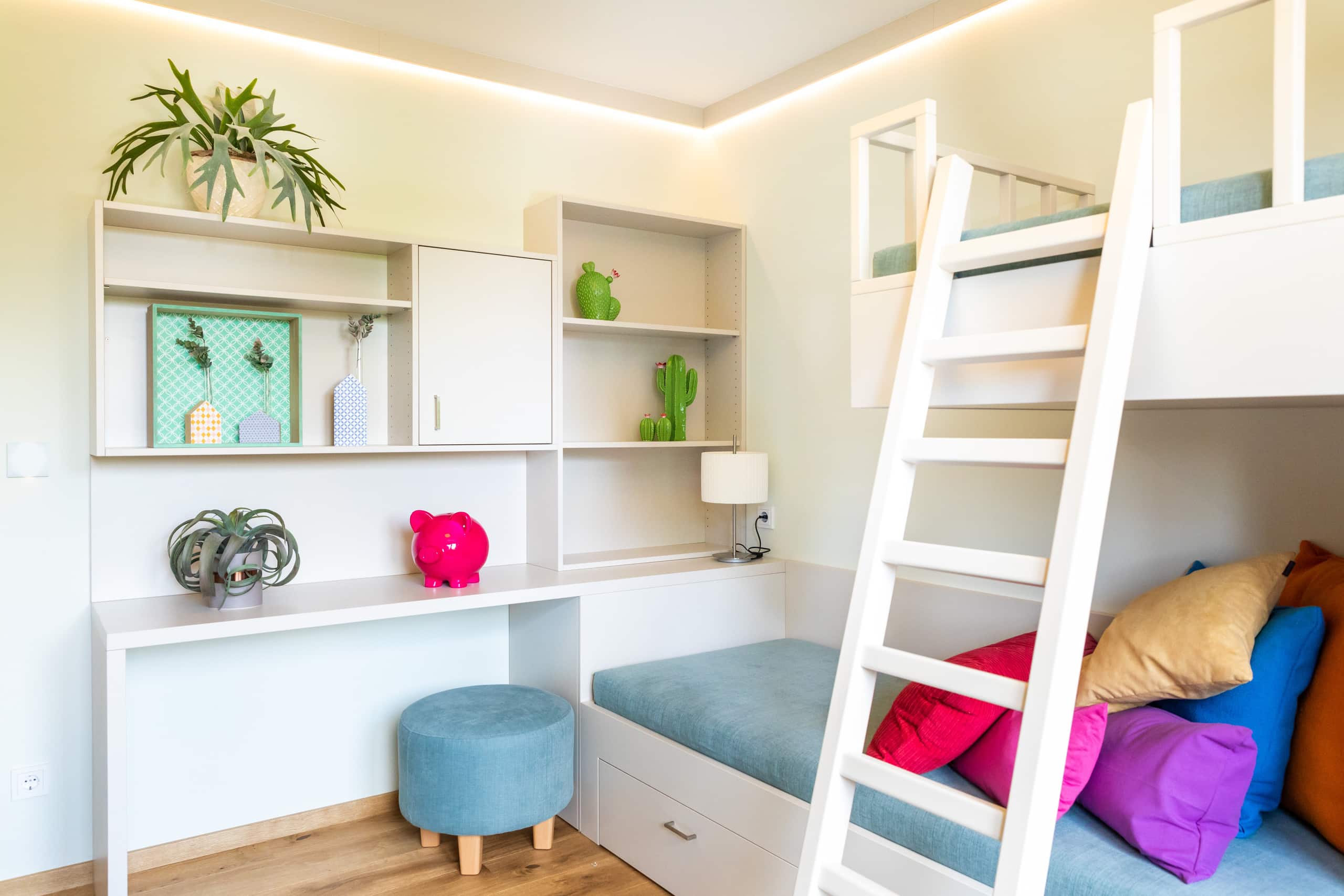 Ein helles, freundliches, kompaktes Kinderzimmer mit beleuchteter Deckenleiste und Schreibtisch-Stockbett-Kombination von HARTL HAUS.
