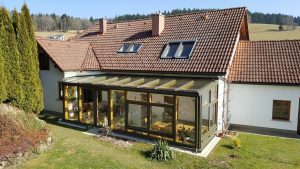 Einfamilienhaus mit angebautem Wintergarten aus Holz und Glas mit verglastem Pultdach von Glaserei Hohl.