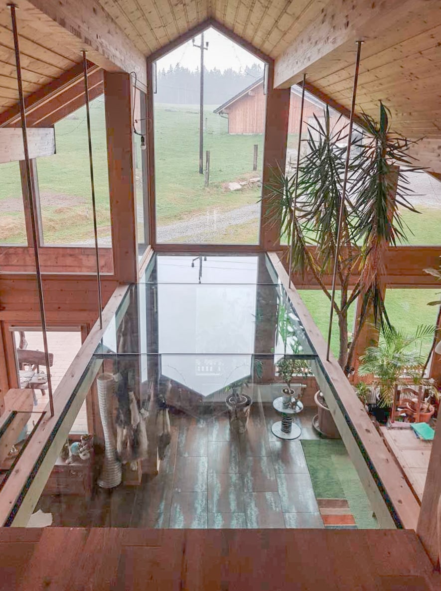 Ein Holzhaus mit Satteldach und einer verglasten Hausfront und einer Zwischendecke aus Glas von Glaserei Hohl.