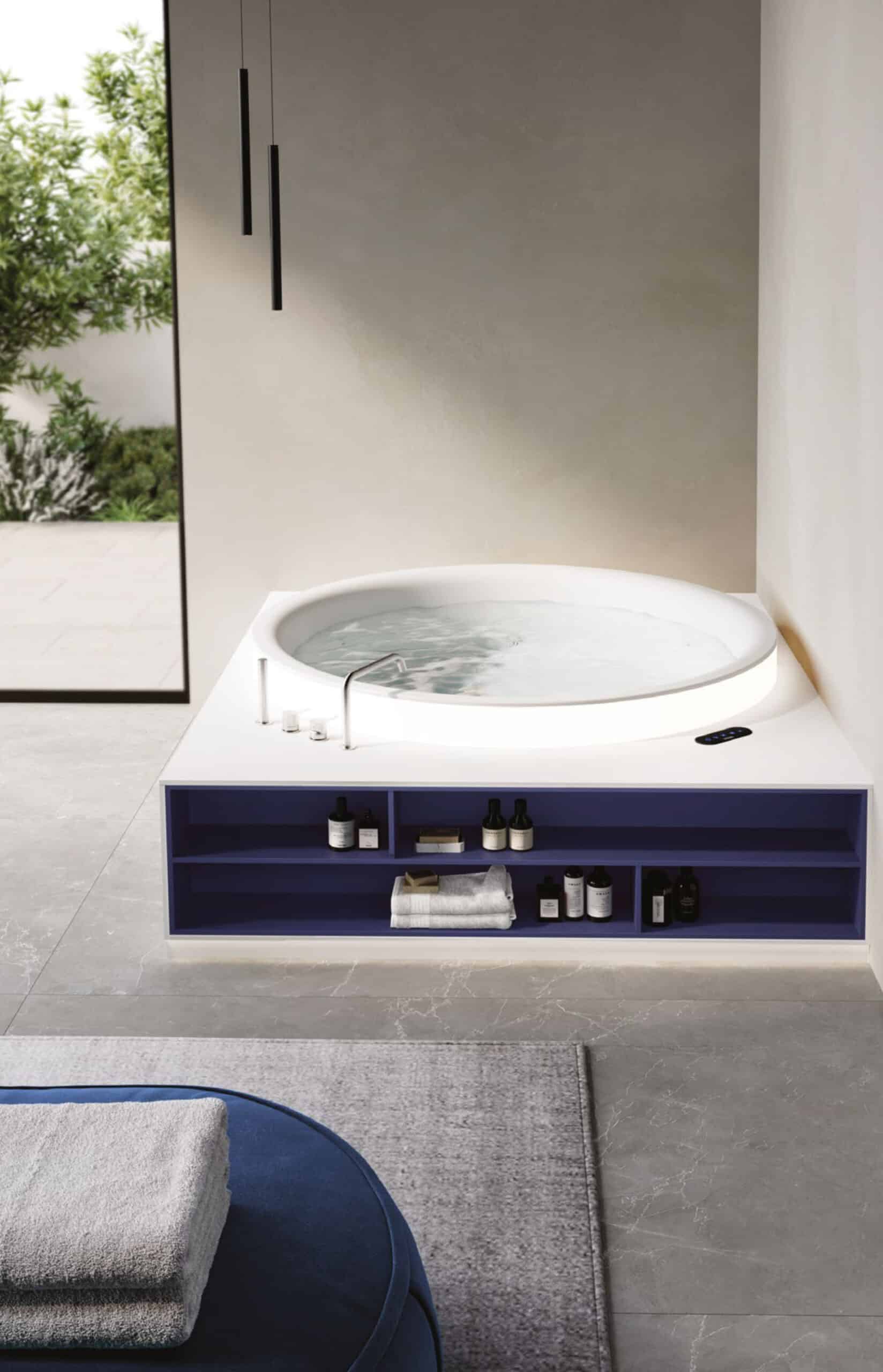 Eine in einem Badezimmer freistehende Whirlpool‑Badewanne und Stauraum in blau aus der Aretusa Wellness Collection von Idea Group.