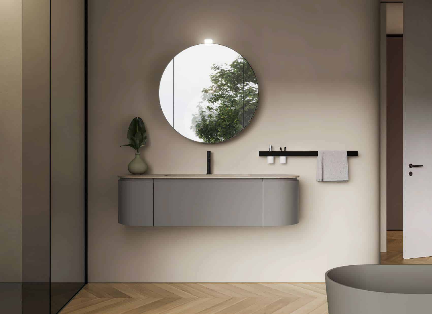 Ein Badezimmer mit grauem ovalen Unterschrank‑Waschtisch, Handtuchhalter und rundem Spiegel Design von Idea Group.