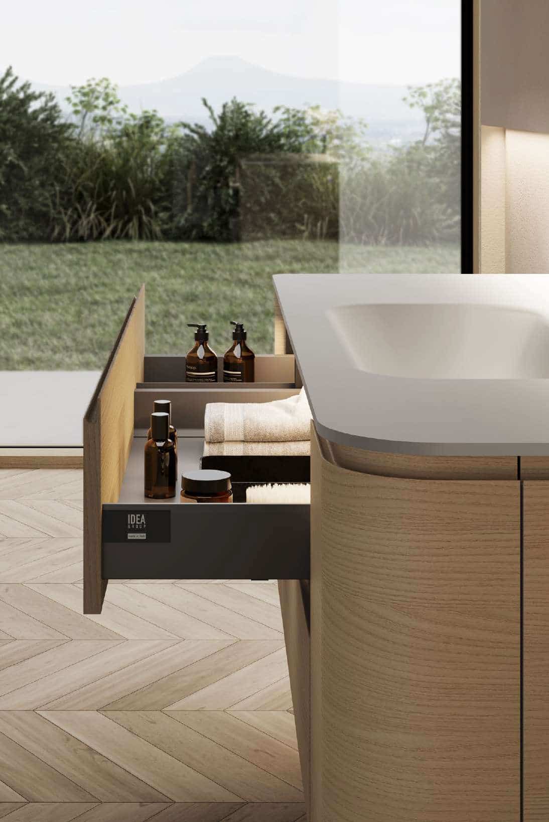 Ein Badezimmer‑Unterschrank aus hellem Holz in ausgezogenem Zustand mit einem gegossenem weissen Waschbecken von Idea Group.