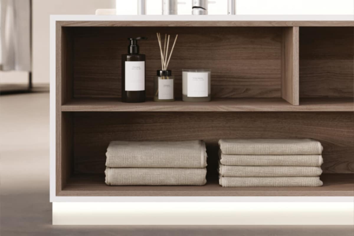Eine weisse Badewanne mit offenem Stauraum und Regalfächern aus Holz von Idea Group.