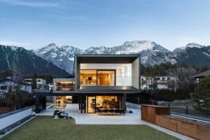 Internorm zeigt eine Villa mit moderner Architektur, Balkon, Terrasse mit Ganzglassystem mit schwarzem Rahmen.