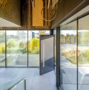 Eingangsbereich einer Villa mit schwarzer Eingangstüre und kompletter Eckverglasung mit schwarzem Alu-Rahmen von Internorm.