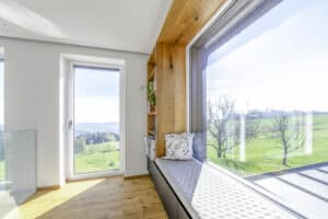 Obergeschoss eines Hauses mit Sitz- bzw. Panoramafenster mit Holzrahmen und integriertem Bücherregal von Internorm.