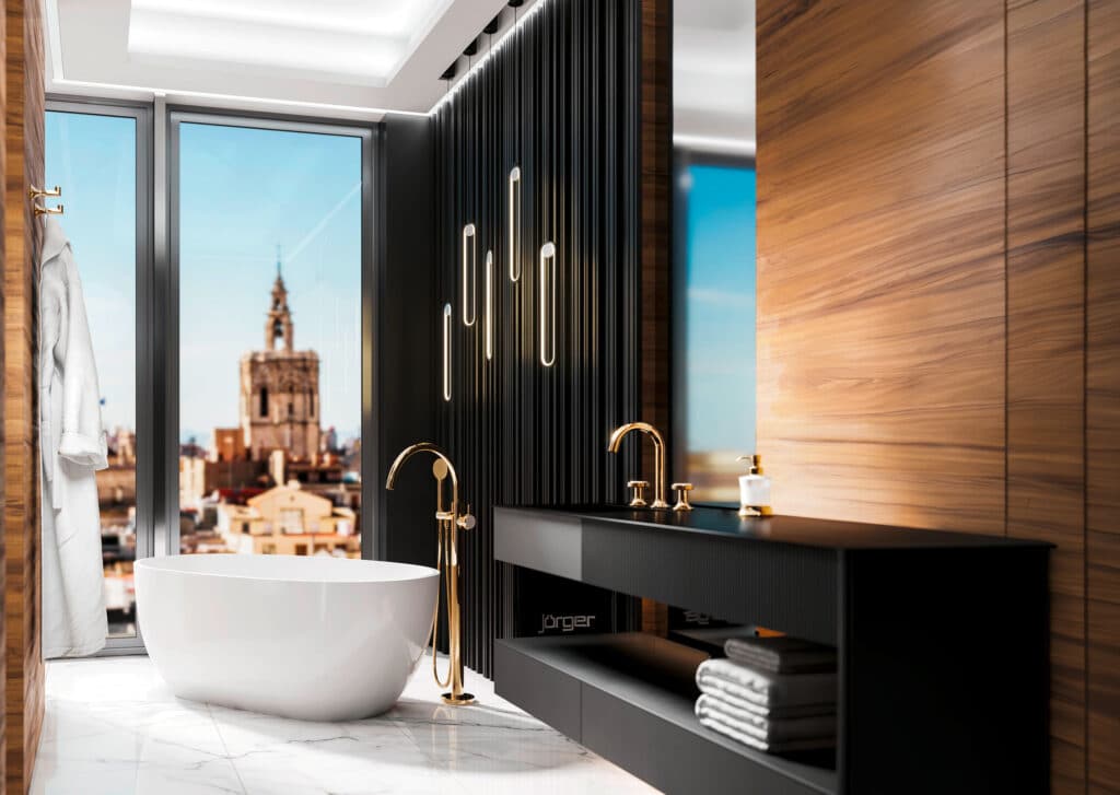 Jörger zeigt ein Badezimmer mit freistehender weißer Badewanne mit freistehender, goldener Wannen-Einhandbatterie und goldener Armatur auf schwarzem Waschtisch.