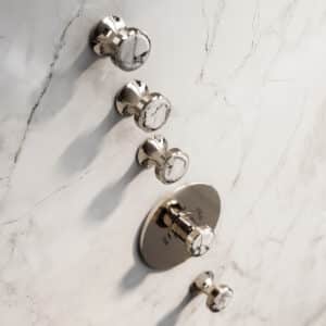 Ein Unterputz‑Thermostat‑Ventil‑Modul aus der Serie 'Valencia' in Platin mit Naturstein‑Detail in weissem Türkis von Jörger.