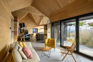 Moderner Wohnraum mit schwarzen Hebeschiebetüren, Holzverkleidung und großzügiger Glasfront von M SORA.