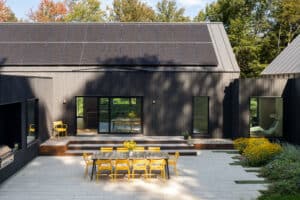 Modernes Haus mit Satteldach, PV-Modulen, schwarzgerahmten Terrassenschiebetüren und großzügigem Hofbereich von M SORA.