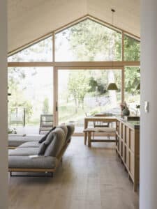 Moderne Wohnküche mit Satteldach, Dachschräge, großer Fixverglasung und Terrassenschiebetür mit schmalem Holzrahmen von M SORA.