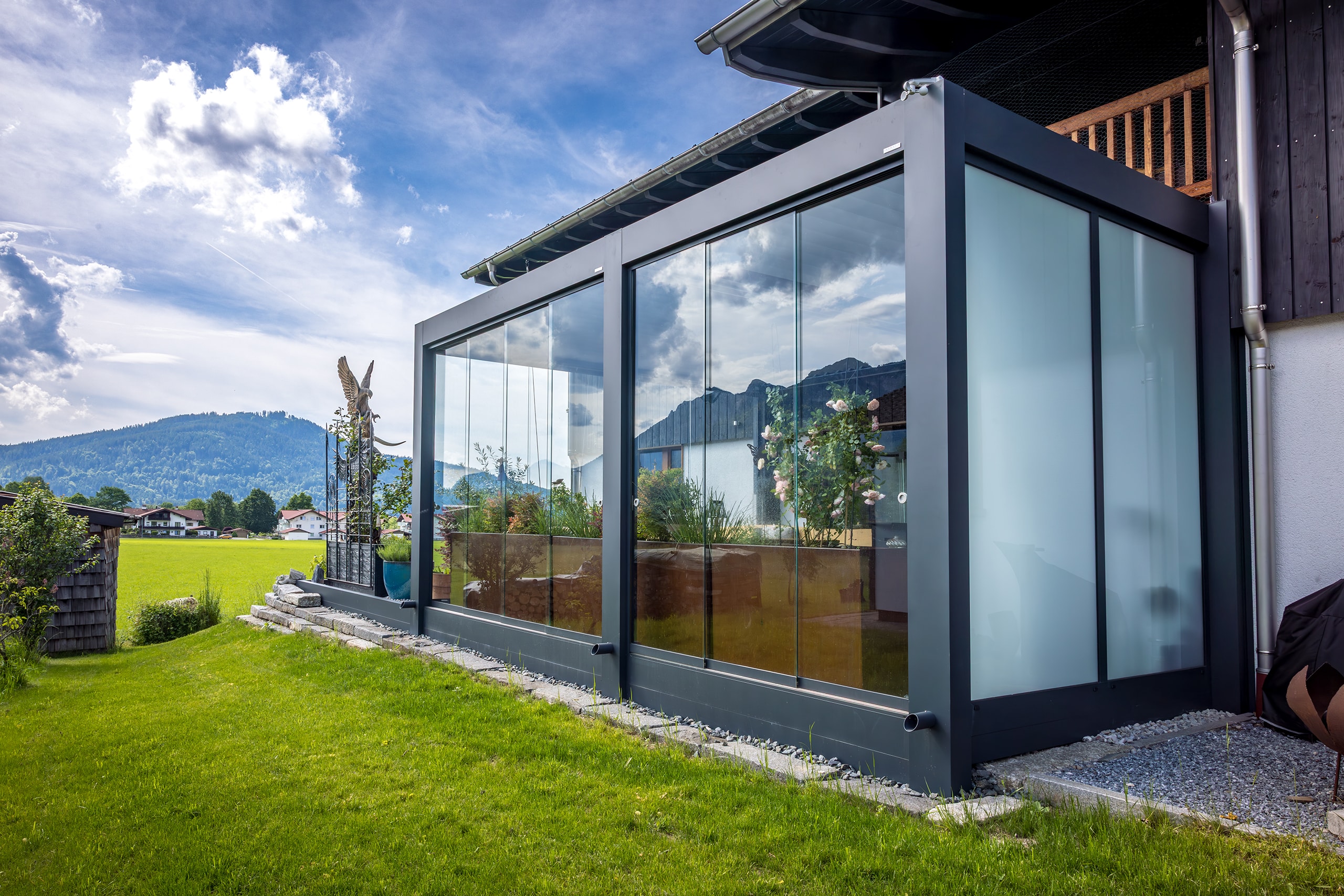 Ein Wintergartenanbau in Anthrazit mit Lamellendach und seitlich geschlossenen Glasschiebetüren von Moltke.