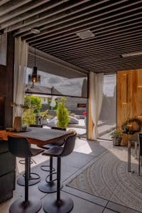 Newo Sonnen- und Insektenschutz zeigt ein Wohzimmer, mit Blick auf die Terrasse und senkrechten Textilscreen-Markiesen, die bis zum Boden reichen.