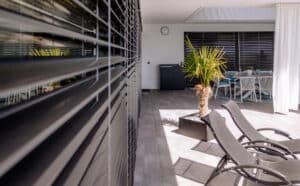 Terrassenbereich mit Verglasung und Terrassentüren mit schwarzem Alu-Rahmen, halbgeschlossenen Raffsstores von Newo.