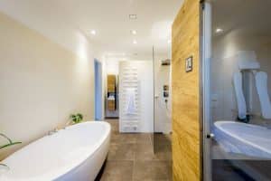 Badezimmer mit freistehender Badewannne, einer Duschnische mit Glastrennwand, einem futruristischen weissem Handtuchwärmer und einer Sauna bzw. Infarotkabine von Planungsbüro Schaufler.