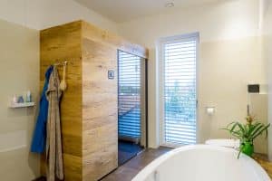 Badezimmer mit freistehender Badewannne, Duschnische, Sauna bzw. Infarotkabine, Toilette, und einem bodentiefen Fenster von Planungsbüro Schaufler.