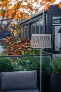 Eine stilvolle Dachterrasse mit Gartenmöbeln, dezenter Stehleuchte und viel Grün von Prachtgarten.