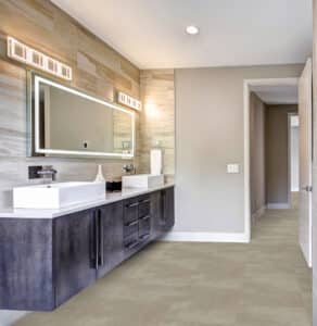 Ein modernes Badezimmer mit durchgehendem Bodenbelag in warmer beigefarbener Steinoptik, der Flur und Wohnbereich stilvoll miteinander verbindet – von project floors.