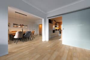 Ein moderner, offener Wohnbereich mit Küche und Esszimmer, durchgehendem Bodenbelag und großzügiger Glasschiebetür – von Project Floors.