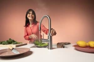 Eine Frau blanchiert Brokkoli mit kochend heissem wasser aus Ihrer Quooker-Armatur in Chrom.