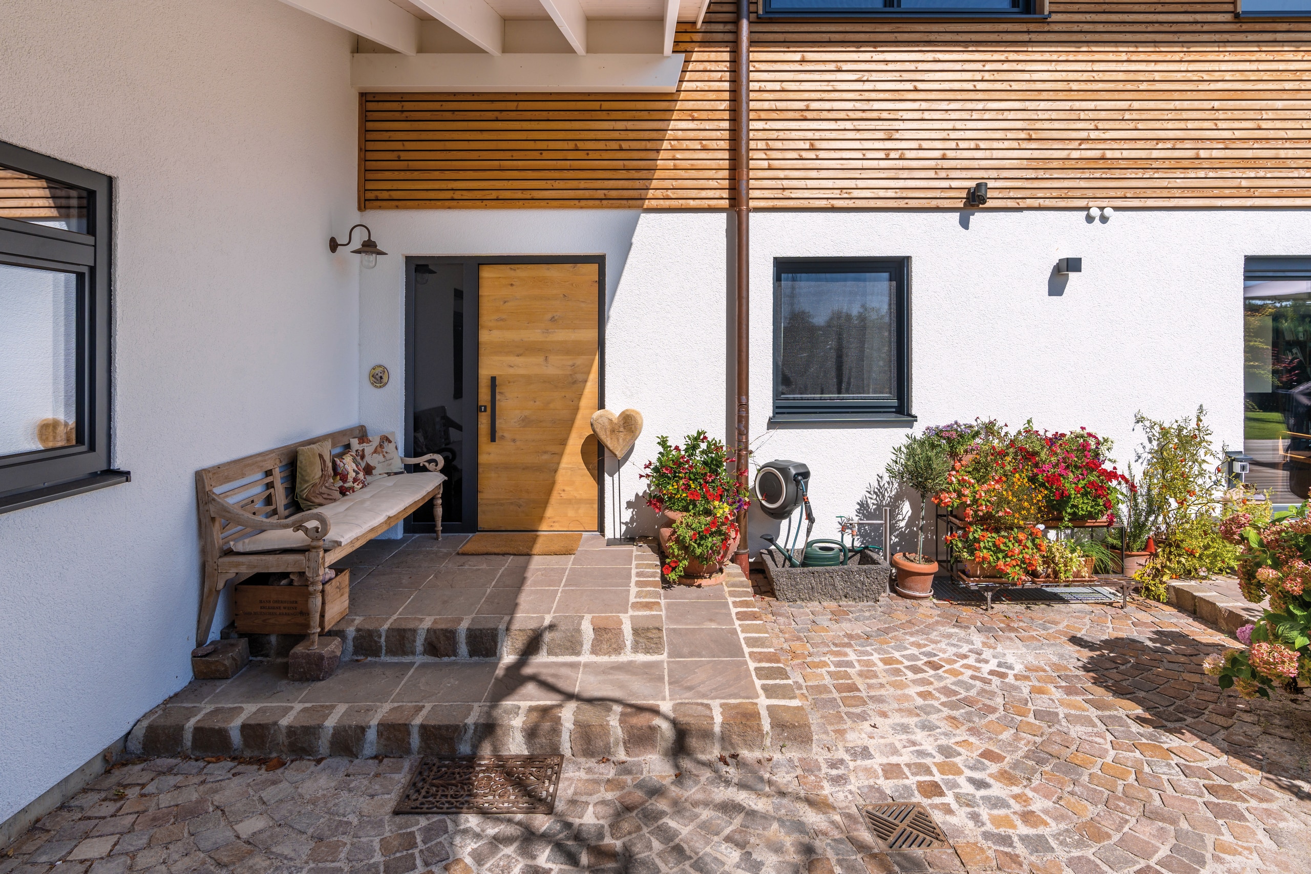Regnauer Fertighaus zeigt Hauseingang eines Einfamilienhauses mit moderner Holztüre und holzverkleideter Fassade.