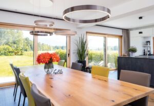 Eine Wohnküche mit Esstisch, gepolsterten Stühlen und einer Terrassenschiebetür in Alu‑Holz‑Rahmen von Regnauer.