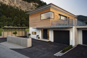 Eine Flachdachvilla mit Dachüberstand, Holzoptik-Fassadenelementen, Eckfenstern, Dachterrasse und integrierter Garage von Regnauer.
