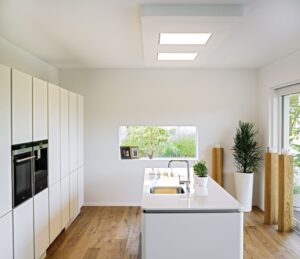 Eine moderne offene Küche mit Kochinsel, bodentiefer Terrassenschiebetür und seitlicher Festverglasung von Regnauer.